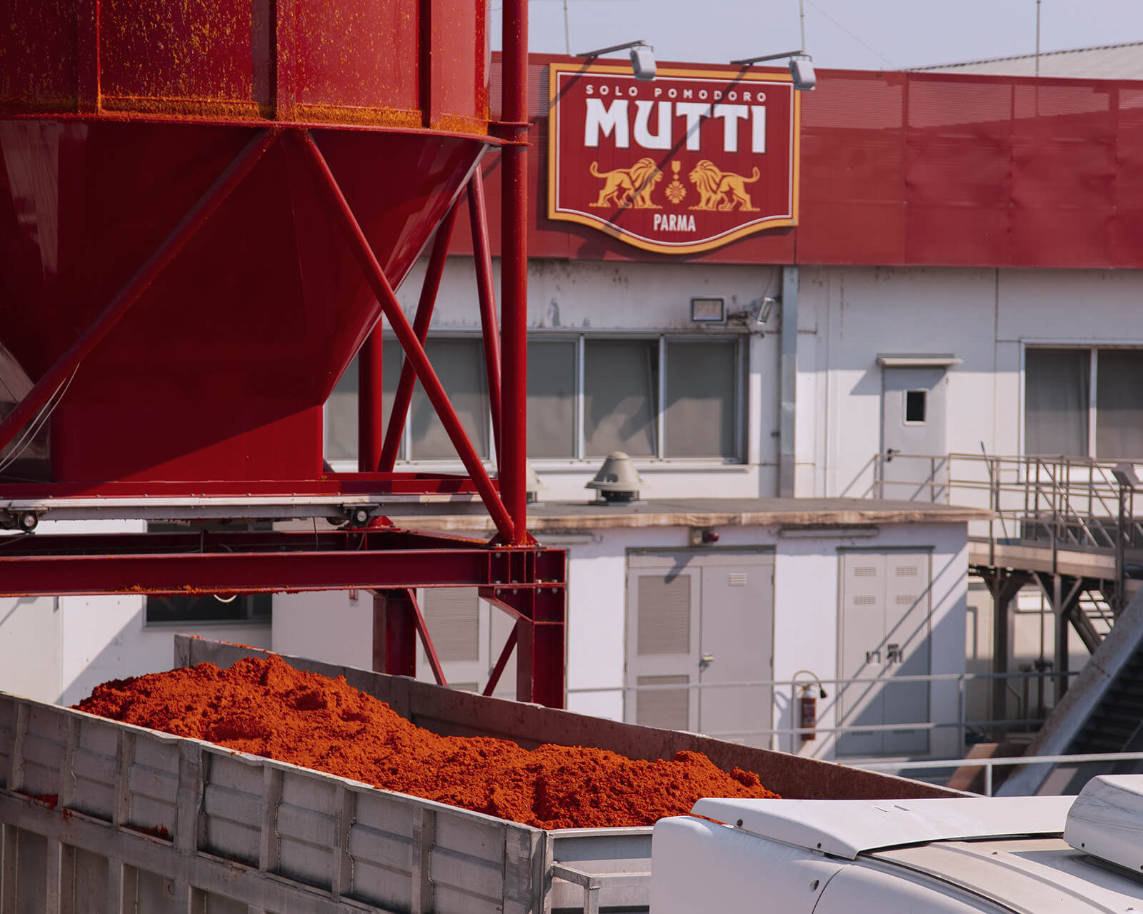 Truck loaded with tomato residue beside a Mutti factory silo
